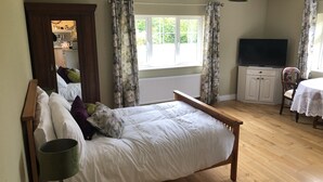 Et soveværelse med seng, fjernsyn, spisebord og et vindue.