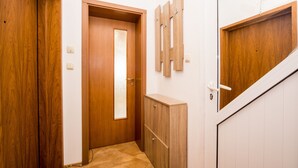 Een gang met houten deuren, een betegelde vloer en een kapstok aan de muur.