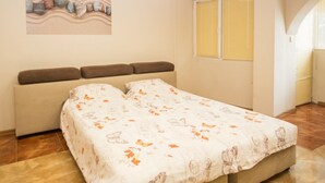 Een slaapkamer met een bed, een bank, een wandairconditioner en een raam met zonwering.