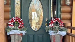 A green door with a white wreath and a bench in front.