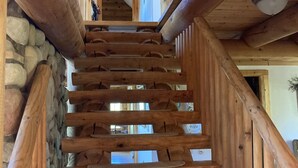 A wooden staircase with stone walls and a view of the upper floor.