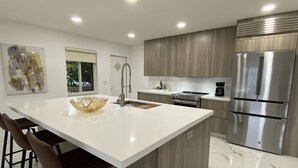 A modern kitchen with a large island, stainless steel appliances, and a minimalist design. - Waterfront condo overlooking Palm Beach (West Palm Beach)