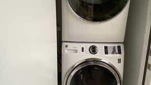 A compact, white stacked washer and dryer unit in a small laundry room. - Waterfront condo overlooking Palm Beach (West Palm Beach)