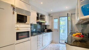 Une cuisine moderne avec des meubles blancs, un four encastré et un four à micro-ondes.