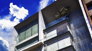A modern building with multiple floors, large windows, and a covered entrance. - Aura For Living (Mexico City)