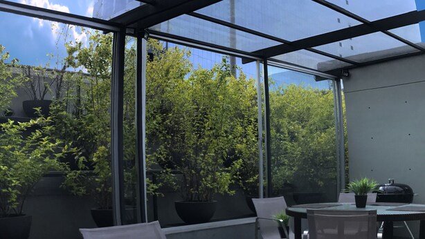 A dining area with a glass table, a plate of watermelon, a glass of orange juice, and a napkin. - Aura For Living (Mexico City)