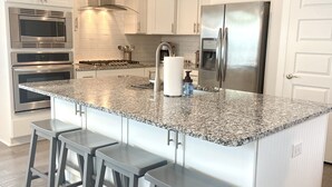 Una cocina moderna con armarios blancos, electrodomésticos de acero inoxidable y encimera de granito.