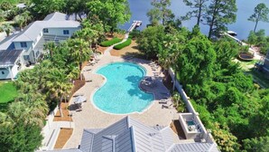 Vista aérea de una zona residencial con piscina, palmeras y un muelle.