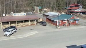 Vista de um edifício com uma placa indicando 'Crow Creek Mercantile' e um estacionamento com vários carros.