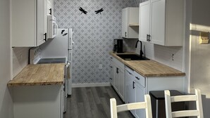 Uma cozinha compacta com armários brancos, bancada de madeira e backsplash estampado.