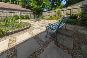 A patio with a stone pathway, a wooden fence, and a bench.
