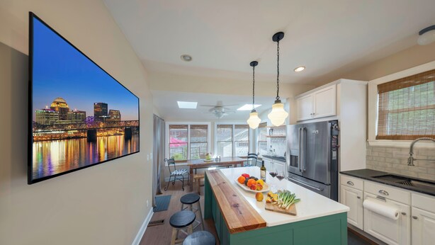 Une cuisine moderne avec vue sur le paysage urbain, un grand îlot central avec des tabourets et un coin repas offrant également une vue.