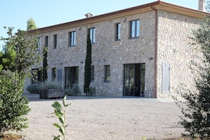 A stone building with multiple windows and a gravel driveway.