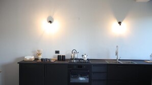 A modern kitchen with black cabinetry, a built-in oven, a kettle, and a sink. - Casa Adele 1 per una Vacanza in Semplicità e Relax (Itri)