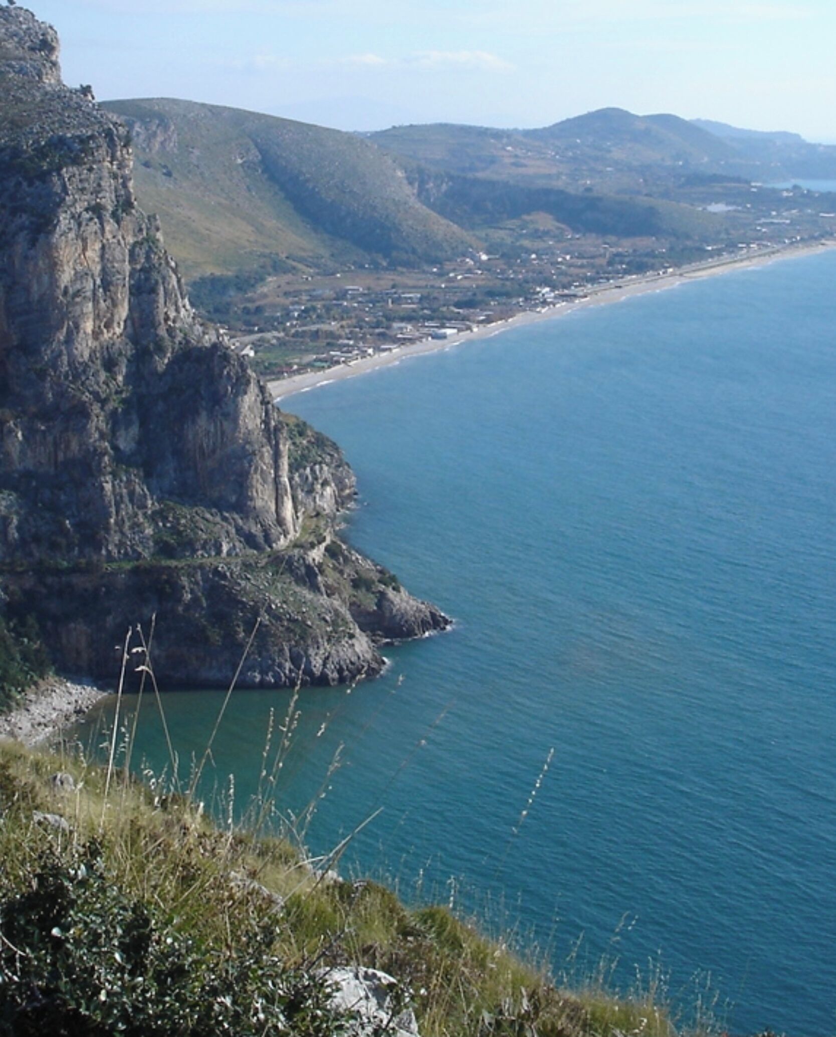Un paysage côtier caractérisé par une falaise imposante et une plage.
