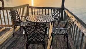 A wooden deck with a round table and four chairs, overlooking a calm body of water during sunset. - Lake Front Estate w/Private Boat Dock on 15 acres - One of a kind! (Alba)