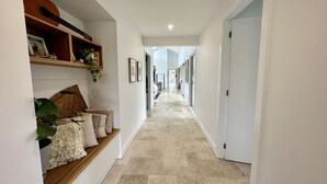 A hallway with a wooden bench, framed pictures, and a plant. - Coastal Retreat - POOL,  SPA & FIRE. Nature boardwalk, creek & inlet. 5 bedroom. (Inverloch)