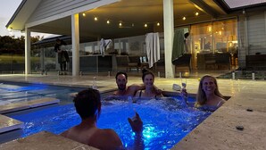 A hot tub area with a pool, outdoor seating, and a covered patio. - Coastal Retreat - POOL,  SPA & FIRE. Nature boardwalk, creek & inlet. 5 bedroom. (Inverloch)