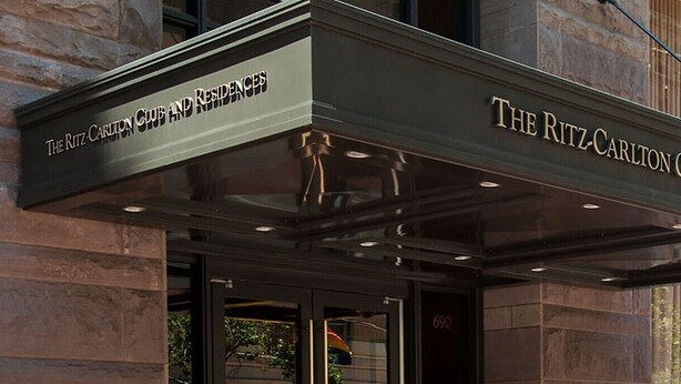 The exterior of The Ritz-Carlton Club and Residences with a prominent entrance and a clear view of the building's stone facade.
