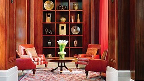 A room with two red upholstered chairs, a wooden coffee table, and a red and white patterned rug.