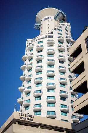 A high-rise hotel with a distinctive cylindrical top, multiple balconies, and a sign indicating it is a Sea Tower.