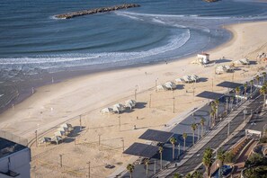 Une plage avec une route, des cabanes de plage et un poste de surveillance pour les sauveteurs.