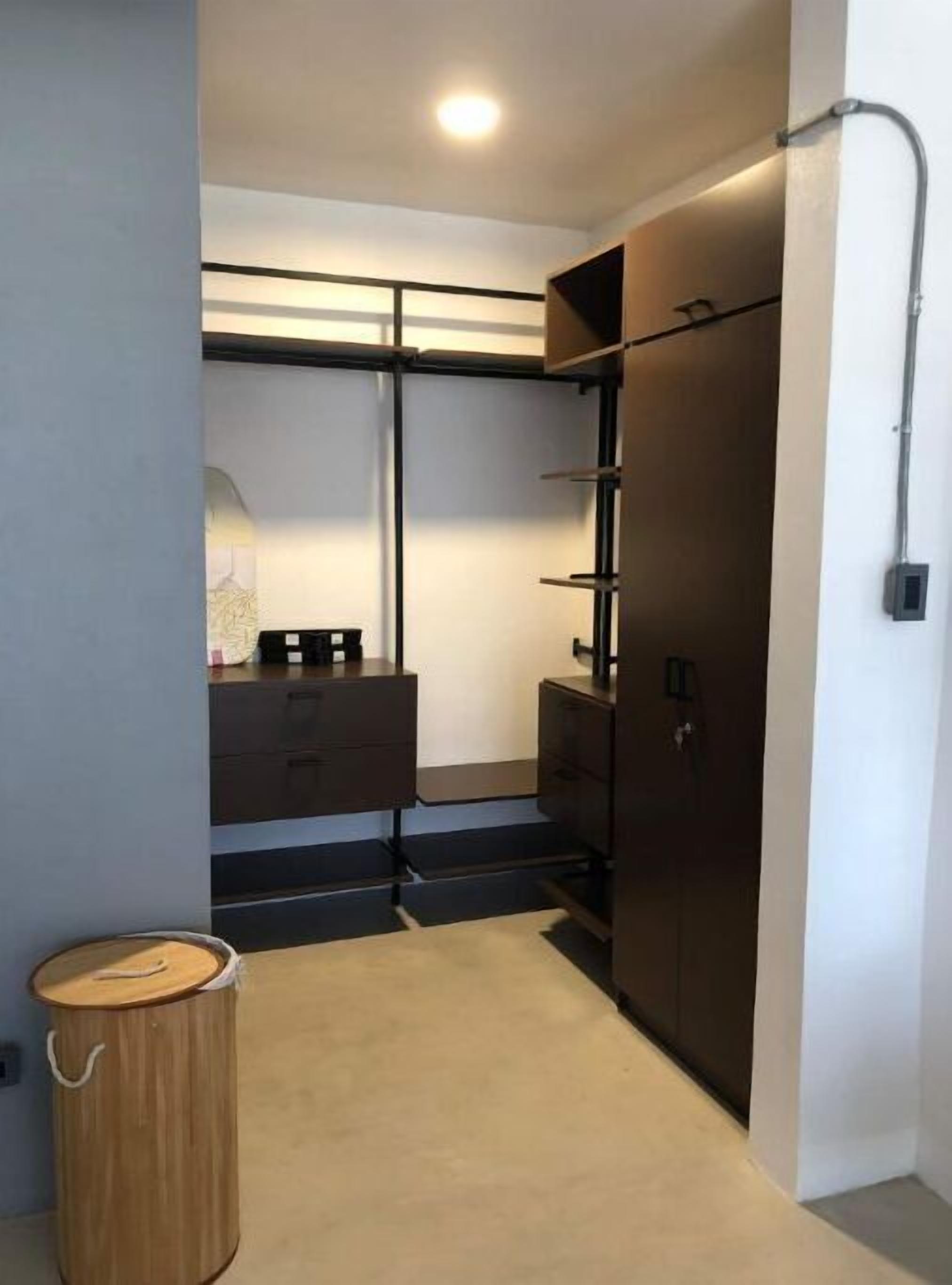 Un dormitorio compacto con armario empotrado, un pequeño escritorio y un cubo de basura.
