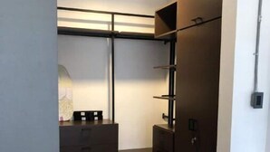 Una camera compatta con armadio a muro, una piccola scrivania e un cestino.