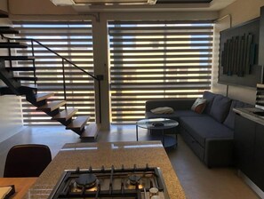 Ein modernes Wohnzimmer mit Gasherd, Sofa, Couchtisch und einer Treppe mit Geländer.