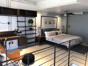 Ein modernes Schlafzimmer mit Bett, Schreibtisch, Stuhl und Regalelement.
