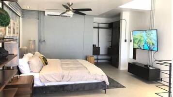 Un dormitorio moderno con cama, ventilador de techo, televisor y armario.
