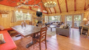 A spacious cabin with a wooden interior, a dining area, a living room with a sofa, and a kitchen area. - Game Room & 2 Decks: Walkable Lake Arrowhead Cabin (Lake Arrowhead)