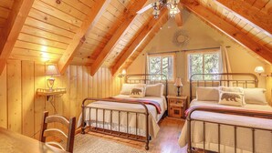 A cozy attic bedroom with two beds, wooden walls, and a sloped ceiling. - Game Room & 2 Decks: Walkable Lake Arrowhead Cabin (Lake Arrowhead)