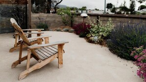 A wooden deck with two Adirondack chairs and a small table.