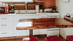 A modern kitchen with a wooden countertop, white cabinets, and red stools.
