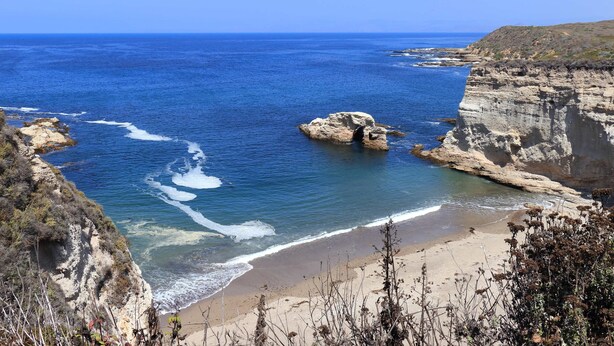Un paisaje costero con acantilados, una playa y el mar.