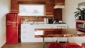 Una cocina moderna con paneles de madera, un refrigerador rojo, armarios blancos, una encimera de madera y una estufa.