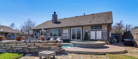 Une maison avec une terrasse en pierre, un jacuzzi et une piscine.