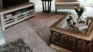 Ein gemütliches Wohnzimmer mit einem Flachbildfernseher, einer Lampe, einem gestreiften Sofa und einem Couchtisch mit Dekoration.