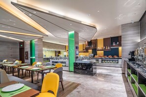 A modern hotel lobby with a central bar area, dining tables, and a kitchen in the background. - Hampton BY Hilton Qinhuangdao Jinmeng (QINHUANGDAO)