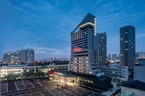 A modern hotel with a distinctive curved facade and a prominent 'Hampton' sign. - Hampton BY Hilton Qinhuangdao Jinmeng (QINHUANGDAO)