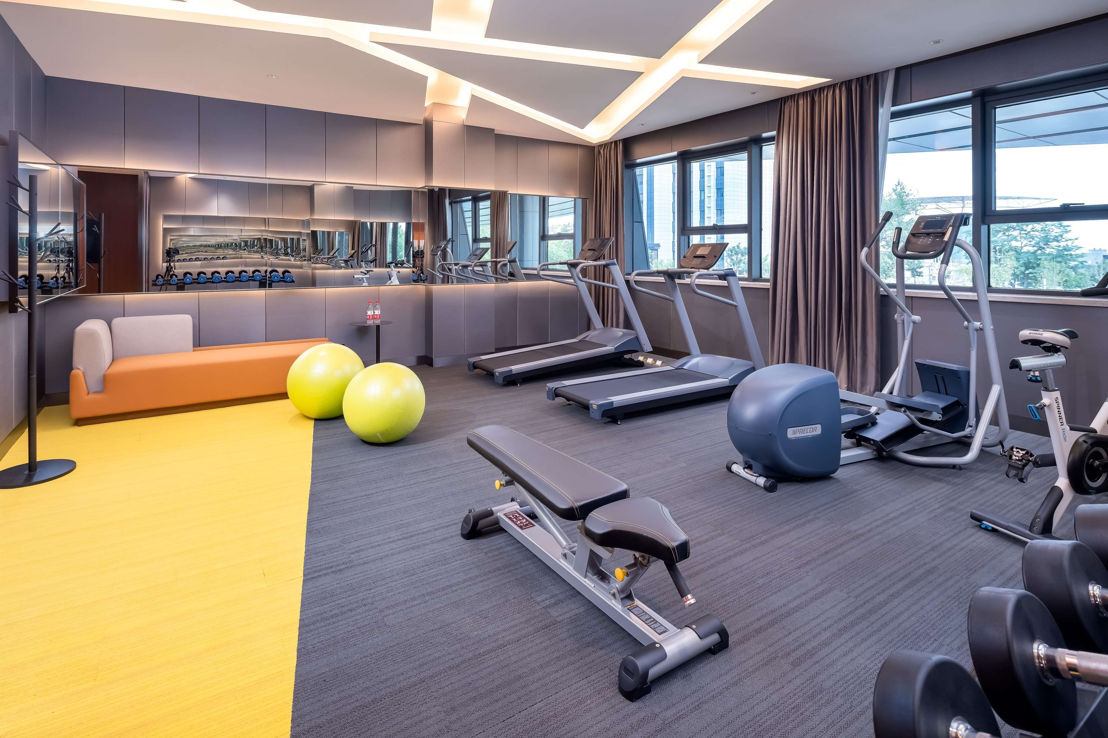 A modern gym with treadmills, elliptical machines, and weight benches.