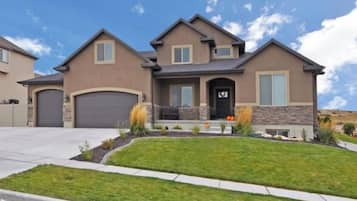 A two-story house with a garage, a front porch, and a well-maintained lawn.