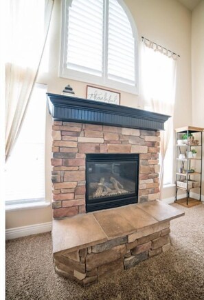 Cozy living room with a fireplace, bookshelf, and large window.