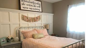 A bedroom with a bed, nightstand, and wall decor.