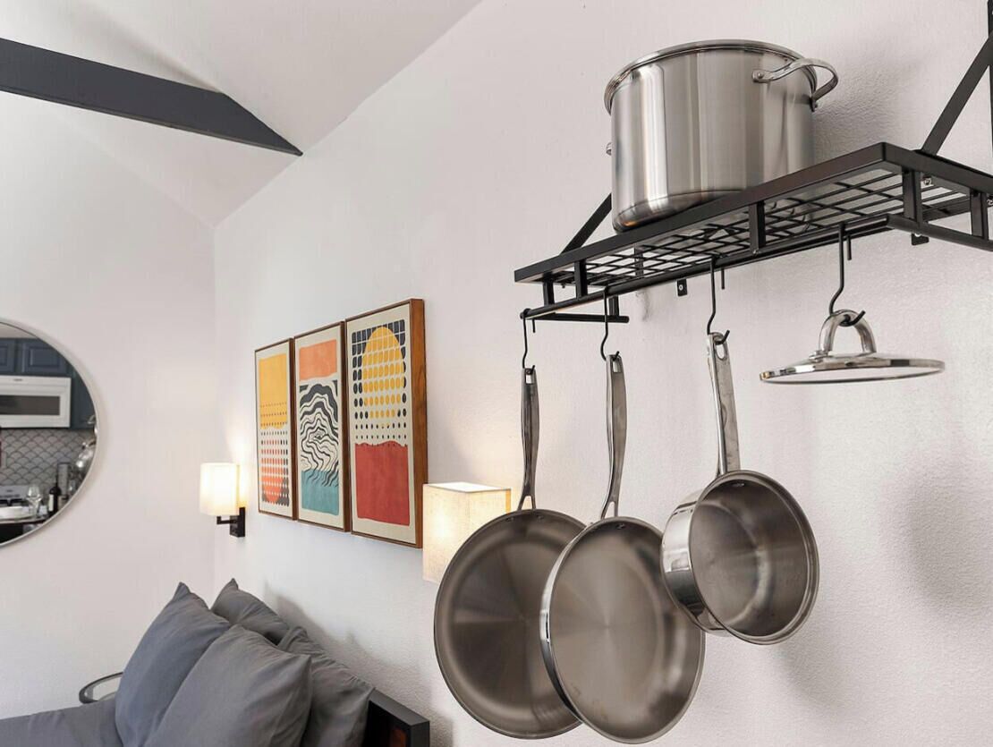 A kitchen with a hanging pot rack, a microwave, and a framed artwork on the wall.