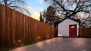 A fenced backyard with a shed and a red door. - Chic Guesthouse Near Downtown | Stylish, Private & Cozy (Chico)