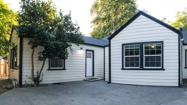 Een tweelaags huis met een voordeur, een zijdeur en een garage.