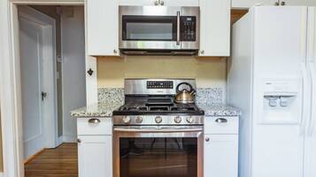 A kitchen with white cabinets, a stainless steel microwave, a gas stove, and a built-in oven.