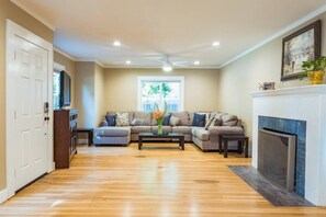 A living room with a sectional sofa, a coffee table, a fireplace, and a television. - Lovely House near Downtown, Your Home away from Home! (Chico)